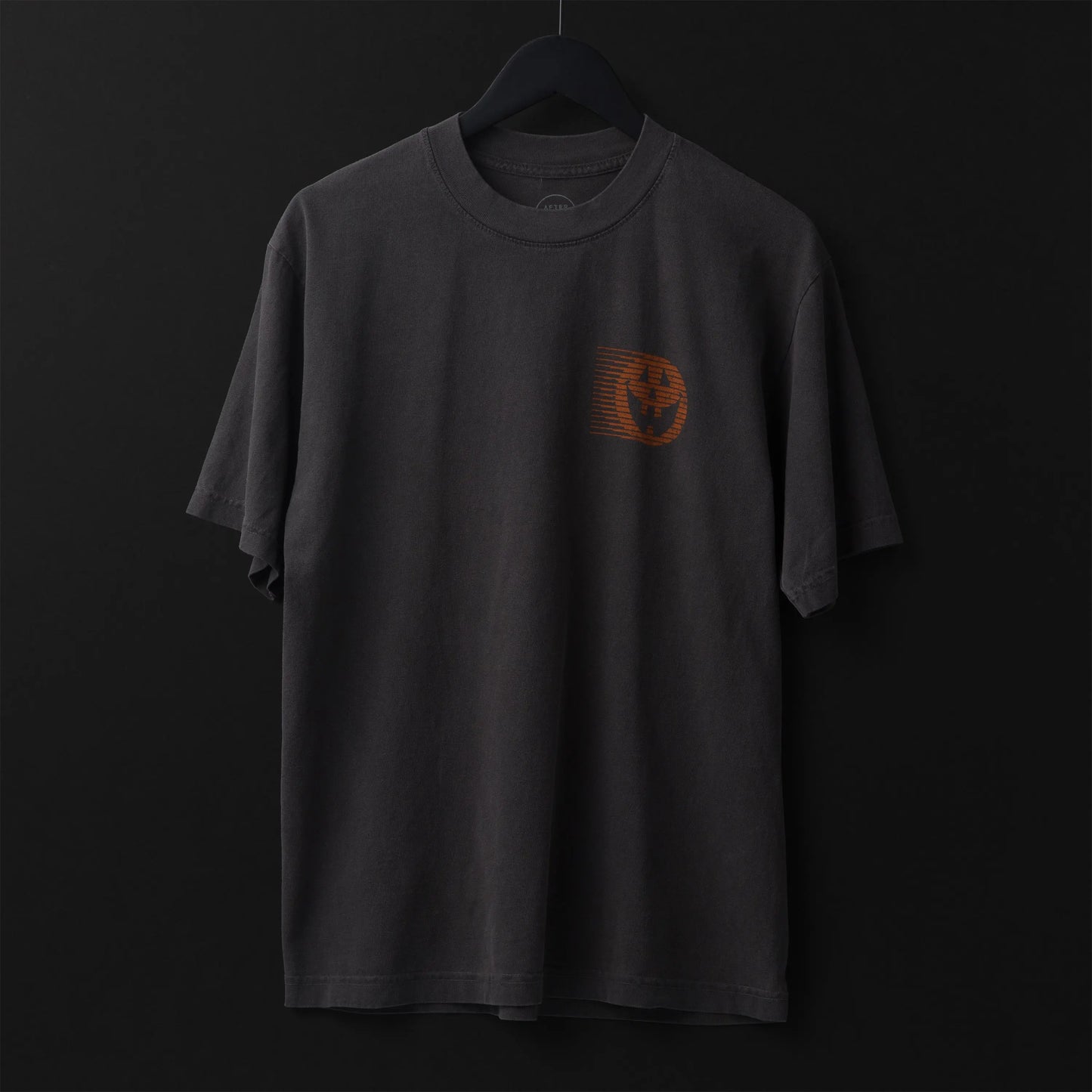 Gray t-shirt with a small orange pumpkin design on a black background