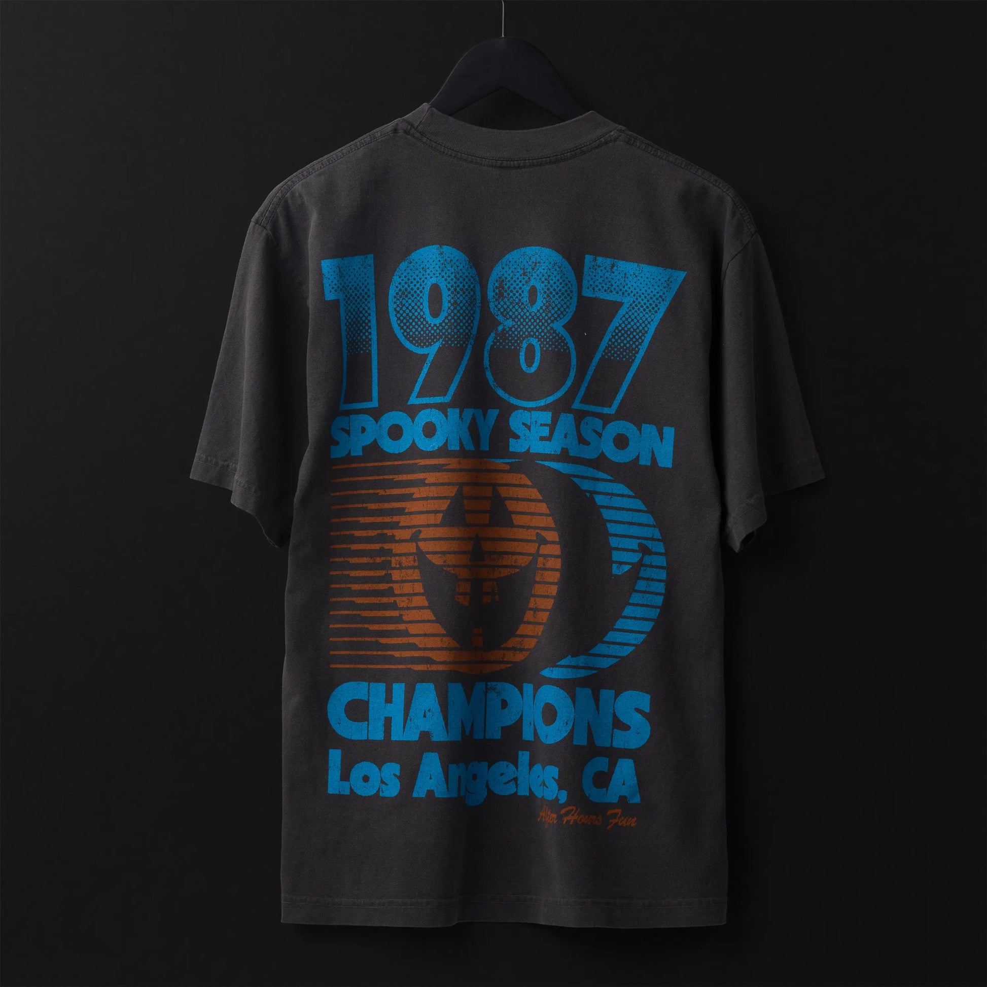 Black t-shirt with blue and orange text and graphics on a dark background